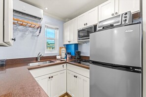 A kitchen with white cabinets, a stainless steel refrigerator, a microwave, and a stove. - Tropic Terrace #51 | Pool-Facing 1BR | Onsite Beach Access + Heated Pool (Treasure Island)
