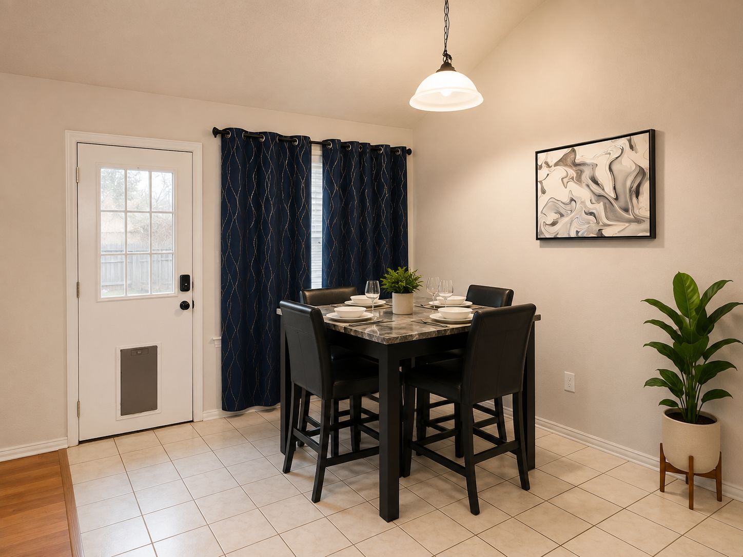 A dining area with a table set for four, a potted plant, and a wall-mounted artwork.