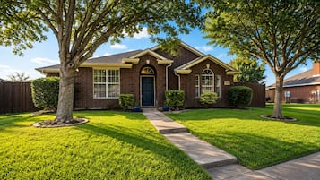 A residential house with a front yard, a driveway, and a well-maintained lawn.