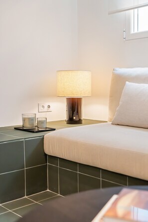 A hotel room with a bed, a nightstand with a lamp, and a small table with a candle and a glass. - Malasaña · Reformado · Gran Vía a 3 min a pie (Madrid)