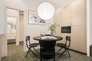 A modern kitchen with a dining table, chairs, a hanging light fixture, and a refrigerator. - Malasaña · Reformado · Gran Vía a 3 min a pie (Madrid)