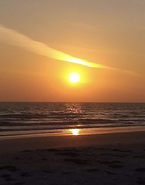 Ein Sonnenuntergang über einem Strand mit Wellen.
