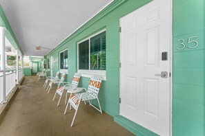 A corridor with white-framed chairs and a white door with the number 35. - Tropic Terrace #35 | 1BR w/ Pool Views | Onsite Beach Access + Great Amenities (Treasure Island)