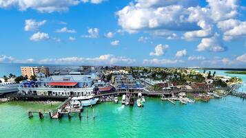 A marina with boats docked, a large building with a red roof, and a clear blue sky.
