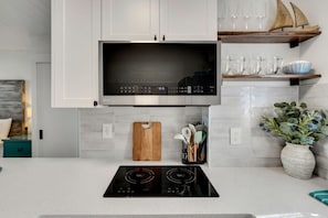 Una cocina moderna con microondas integrado, estufa y tabla de cortar de madera.