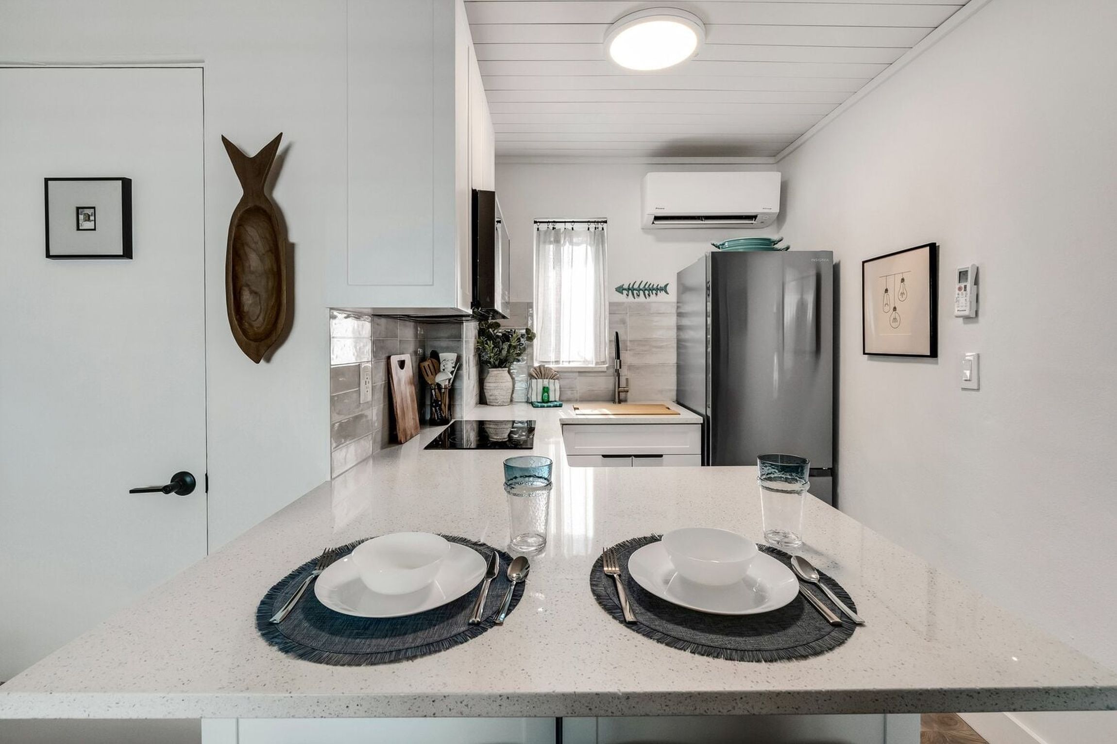 A modern kitchen with a central island, white cabinetry, and a stainless steel refrigerator.