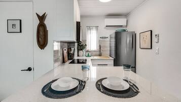 A modern kitchen with a central island, white cabinetry, and a stainless steel refrigerator.
