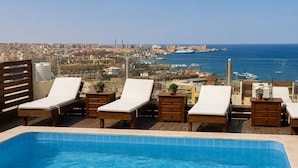 Zona de piscina al terrat amb gandules i vista a la ciutat i al mar.