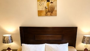 Habitació d'hotel amb un llit gran, dues taules de nit, làmpades, un quadre i tovalloles damunt del llit.