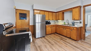 Una cucina con mobili in legno, un frigorifero in acciaio inossidabile, forno integrato e microonde.