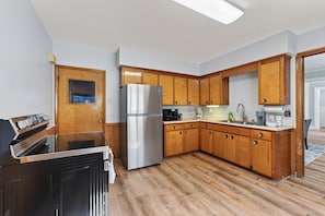 A kitchen with wooden cabinets, a stainless steel refrigerator, a built-in oven, and a microwave. - Minutes To The Falls! Cozy Retreat Near State Park 3 Bedroom Apts (Niagara Falls)