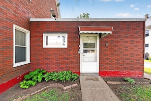 A red brick building with a white door, a small window, and a mailbox. - Minutes To The Falls! Cozy Retreat Near State Park 3 Bedroom Apts (Niagara Falls)