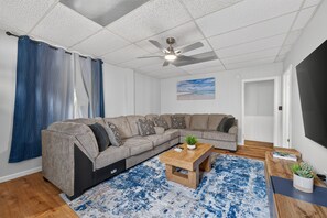 Uma sala de estar moderna com sofá seccional, mesa de centro e ventilador de teto.