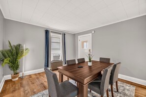 A conference room with a wooden table, grey chairs, a potted plant, and a window with blinds. - Minutes To The Falls! Cozy Retreat Near State Park 3 Bedroom Apts (Niagara Falls)