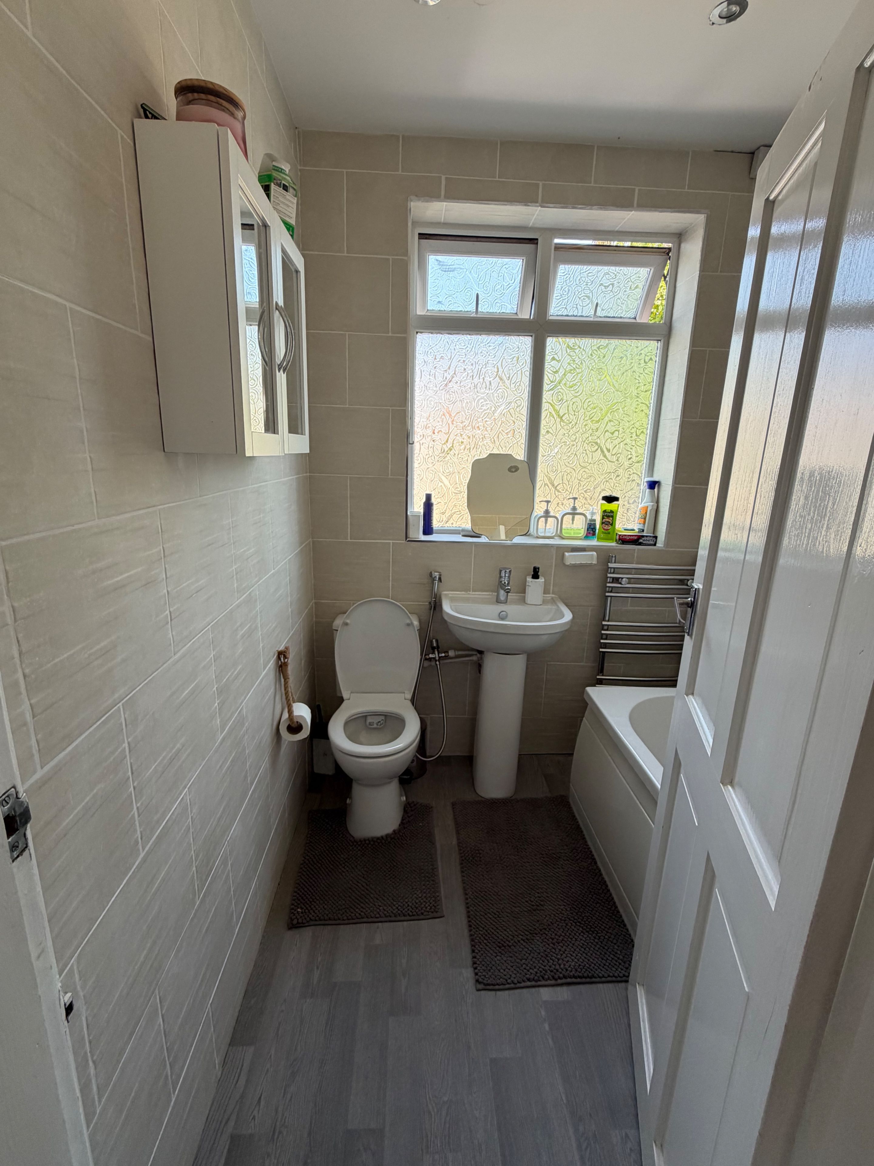 A compact bathroom with a toilet, sink, and window.