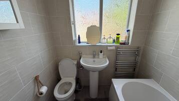 A compact bathroom with a toilet, sink, and bathtub.