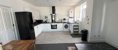 Cocina moderna con alacenas blancas, refrigerador negro, microondas, estufa y lavadora.