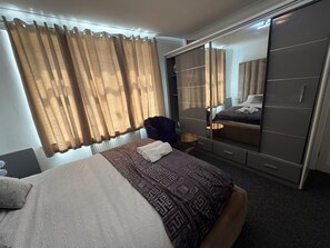 Habitación de hotel con cama, armario, una silla y una mesita.