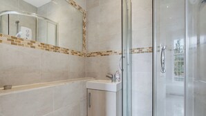 Ein modernes Badezimmer mit Glasdusche, Waschbecken und Spiegel mit dekorativer Fliesenumrandung.