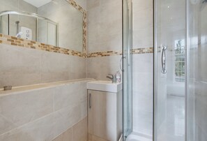 A modern bathroom with a glass shower enclosure, a sink, and a mirror with a decorative tile border. - Arsenal Corner Studio, 4 minutes to Kings Cross, with Ensuite & Self Check-In (London)