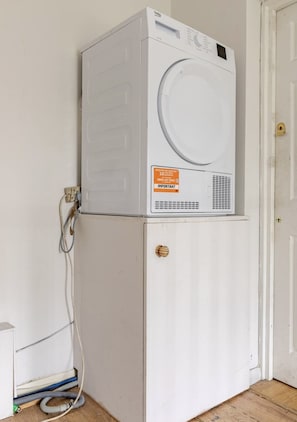 A stacked washer and dryer unit with a door and a label on the dryer. - Arsenal Corner Studio, 4 minutes to Kings Cross, with Ensuite & Self Check-In (London)