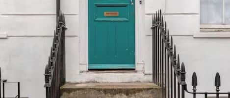 A set of stone steps leading to a teal door with a small window above it.