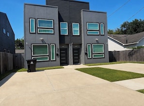 A modern two-story house with a garage, a front yard, and a trash bin. - H-Town Dream Deluxe Stay (Houston)