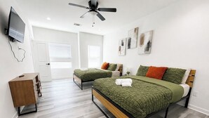 Ein Schlafzimmer mit zwei Betten, einem Deckenventilator, einem Fernseher und einer hölzernen Kommode.
