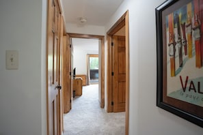 A hallway with wooden doors, a framed picture on the wall, and a carpeted floor. - Ski Hill Powder Retreat: Downtown Breck, Walk to Gondola (Breckenridge)