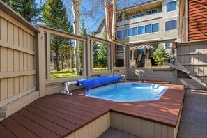 A hot tub with a wooden deck, surrounded by a wooden fence, and a building in the background. - Ski Hill Powder Retreat: Downtown Breck, Walk to Gondola (Breckenridge)