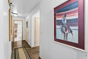Ein Flur mit Holzboden, Teppich und einem gerahmten Gemälde an der Wand.