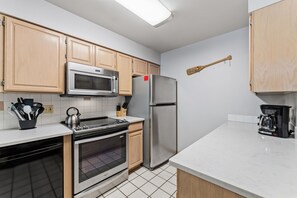 Eine moderne Küche mit Edelstahlgeräten, Holzschränken und einer gefliesten Spritzschutzwand.