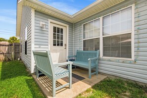Ein Haus mit Veranda, einer Tür, zwei Fenstern und einer Bank.