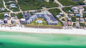 Vista aérea de un hotel costero con varias construcciones, una piscina central y una playa.