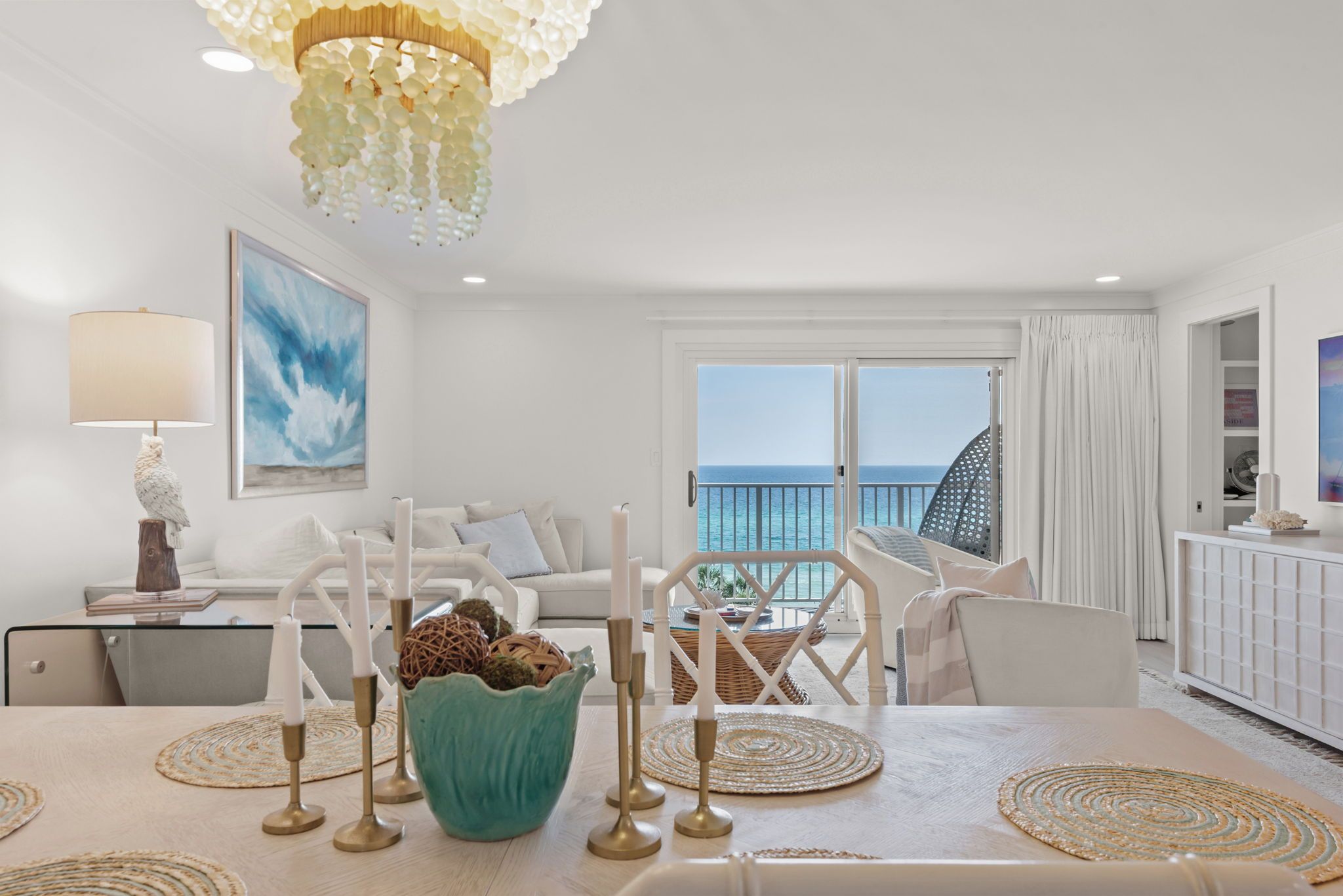 Een moderne woonkamer met uitzicht op zee, een eethoek met een tafel voor vier personen, en een balkon met een hekwerk.