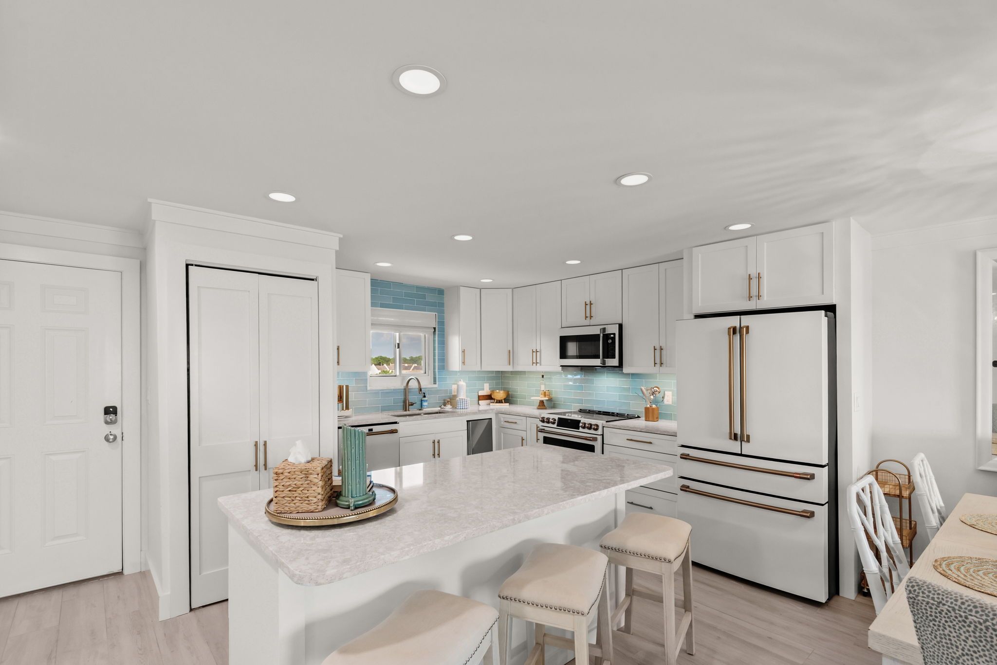 A modern kitchen with white cabinetry, a central island, and stainless steel appliances.