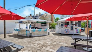 A patio area with outdoor seating, a food kiosk, and a snowball machine. - 2BR Beachfront 30A Condo | Private Beach, Pool & Tennis (Seacrest)