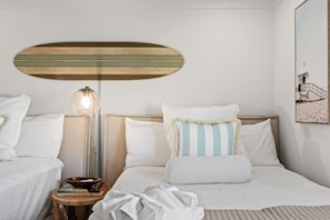 A hotel room with two beds, a bedside table with a lamp, and a wall-mounted artwork. - 2BR Beachfront 30A Condo | Private Beach, Pool & Tennis (Seacrest)