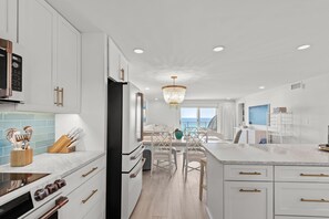 Una cocina moderna con muebles blancos, una isla central y vistas al mar.