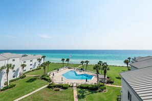 Un complex turístic amb piscina, palmeres i vista a l'oceà.
