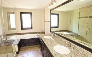 Une salle de bain avec deux lavabos, un grand miroir et un espace douche.