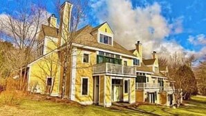 A large, two-story house with a prominent chimney, a balcony, and a well-maintained lawn. - Warm, inviting condo 5 mins to Mt Snow. Dog-friendly, 2 fireplaces, Great wifi⛄️ (Wilmington)