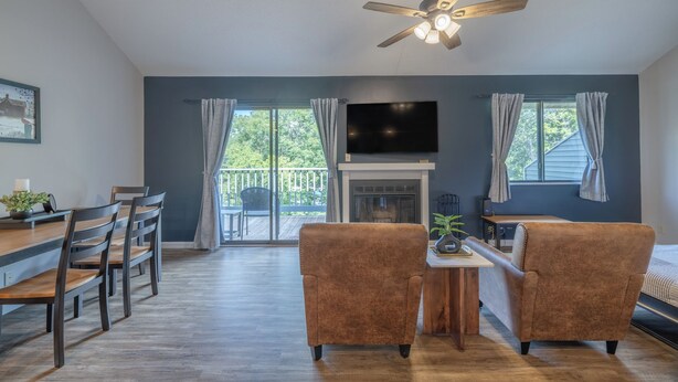 A modern living room with a fireplace, a TV mounted on the wall, and a balcony with curtains. - Lake Aspen Getaway by Innsbrook Vacations! (Innsbrook)