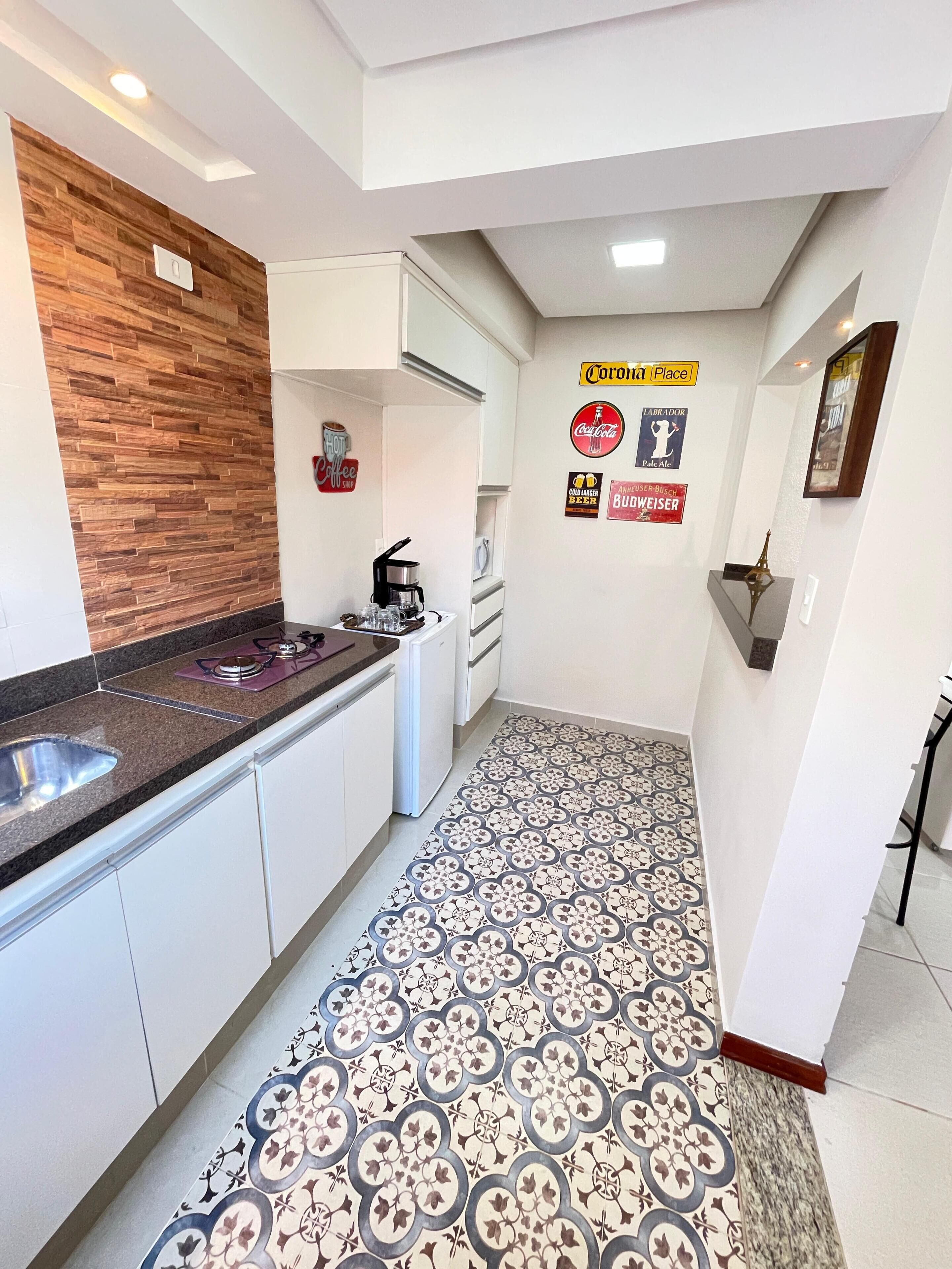 Une cuisine moderne avec des armoires blanches, un mur d’accent en bois et un sol à motifs.