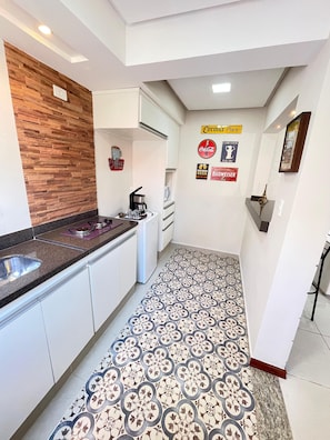 Een moderne keuken met witte kasten, een accentmuur van hout en een vloer met een patroon.