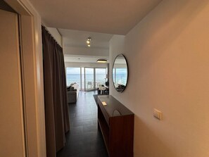 A hotel corridor with a view of the sea, a seating area, and a large mirror on the wall. - House Zur Mole, Apartment 13 "sea View" (Grossenbrode)