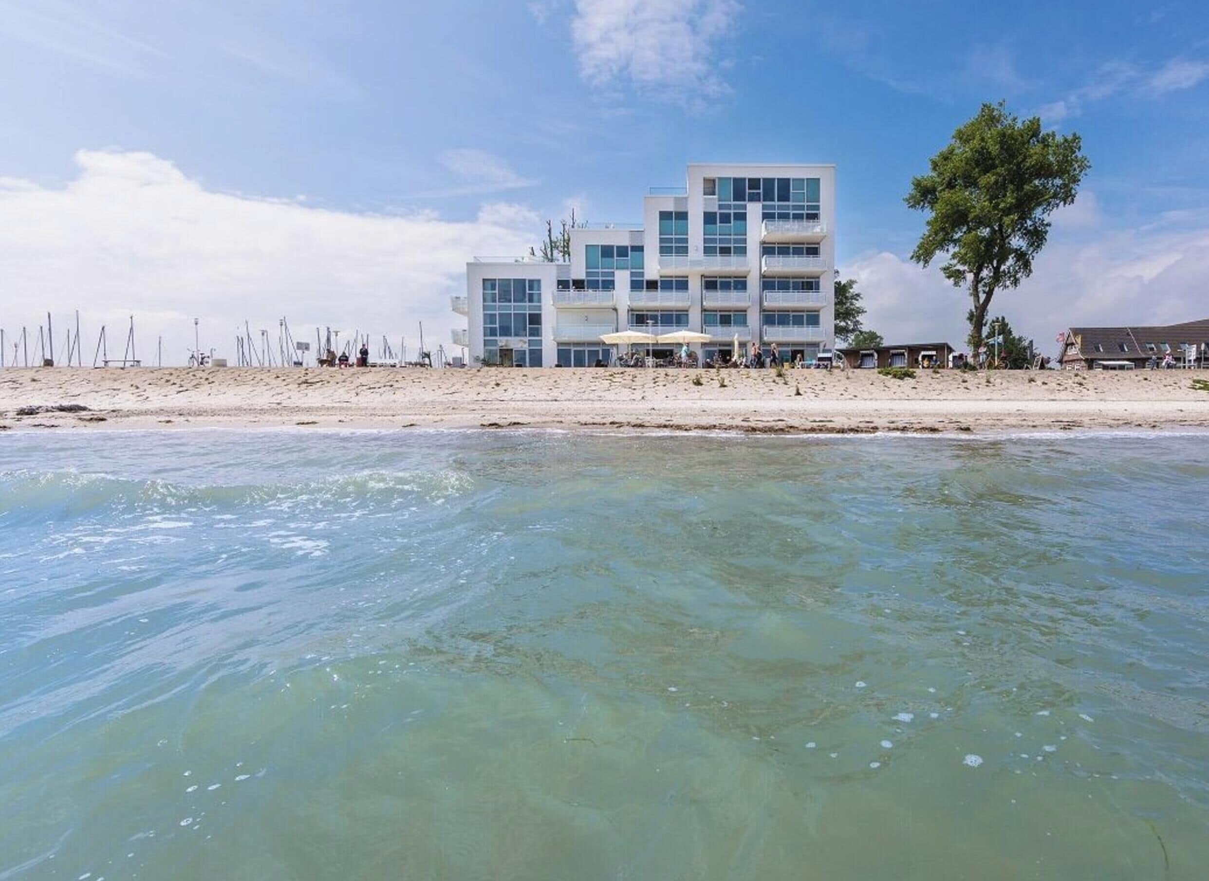 A beachfront hotel with a modern design, featuring multiple balconies and large windows.