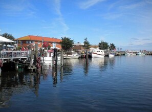 A marina with boats docked, a building with a red roof, and a clear blue sky. - House Zur Mole, Apartment 13 "sea View" (Grossenbrode)