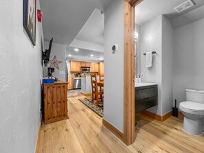 Un pasillo que conduce a una cocina con armarios de madera, un microondas y una zona de comedor.