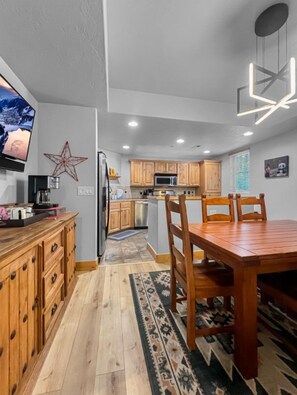 Una cocina moderna con armarios de madera, una mesa de comedor y un televisor montado en la pared.